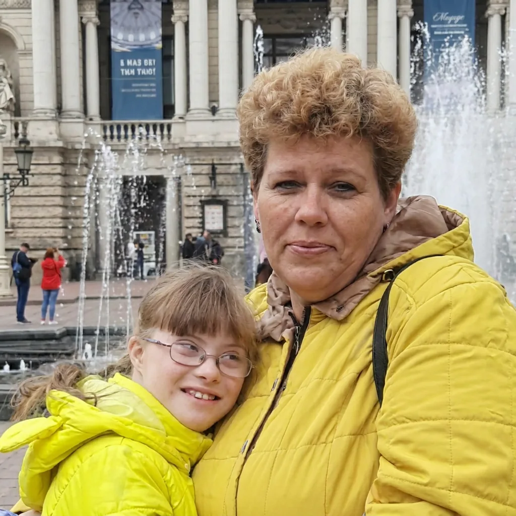 A mother hugging her daughter by a fountain